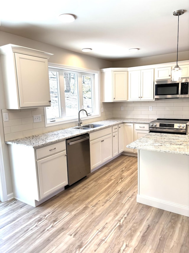 247 Sandlewood Dr, East Stroudsburg, PA 18301 - kitchen featuring light wood-style floors, tasteful backsplash, a sink, decorative light fixtures, and stainless steel appliances