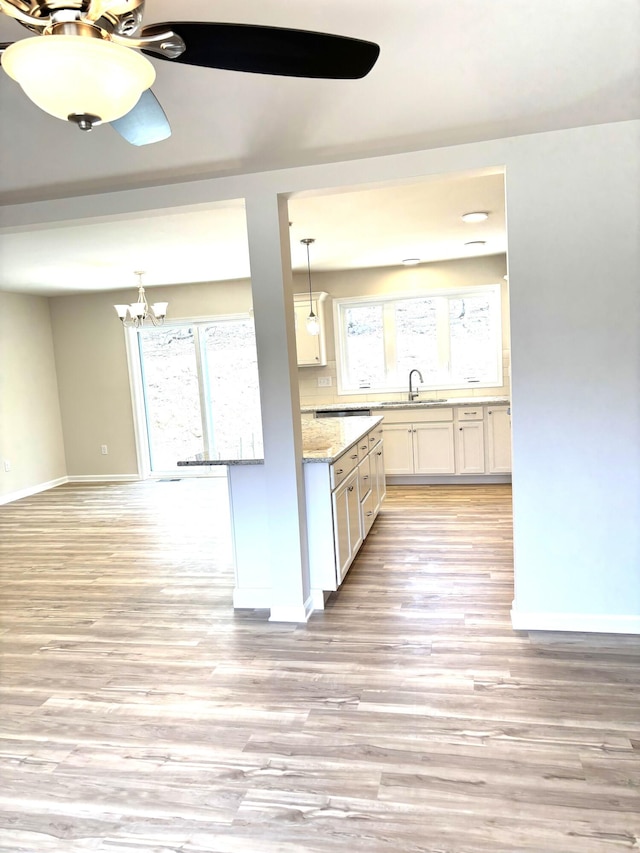247 Sandlewood Dr, East Stroudsburg, PA 18301 - kitchen with hanging light fixtures, a sink, light wood finished floors, white cabinetry, and baseboards