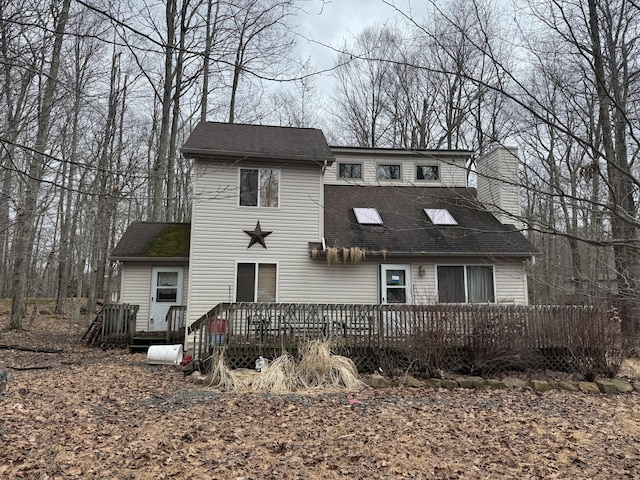 view of front of home featuring a wooden deck and roof with shingles