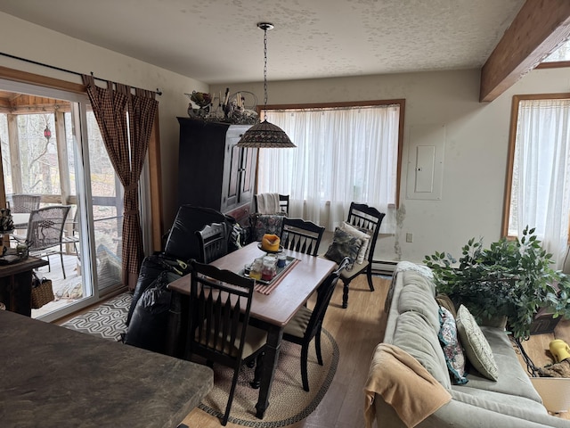 dining area featuring a baseboard heating unit, electric panel, wood finished floors, and a textured ceiling