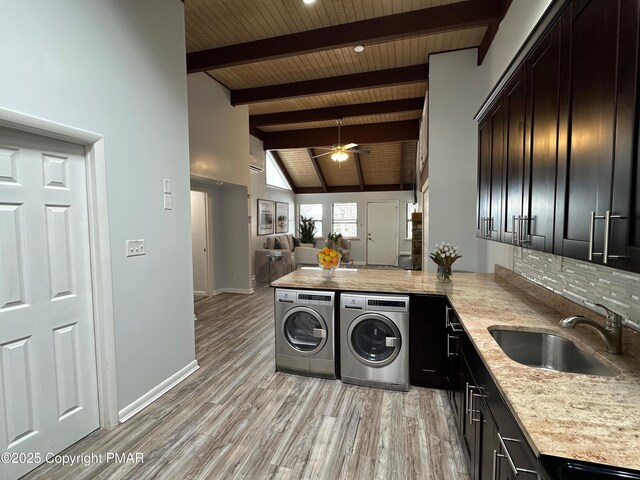 kitchen featuring a sink, baseboards, open floor plan, light wood-style floors, and independent washer and dryer