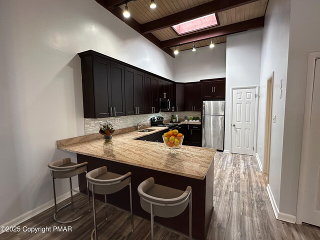 kitchen with stainless steel appliances, a skylight, a sink, and decorative backsplash