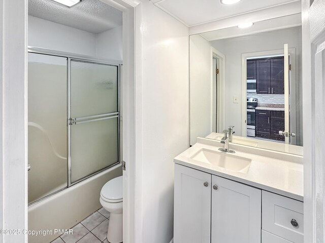 full bath featuring bath / shower combo with glass door, toilet, tile patterned floors, a textured ceiling, and vanity