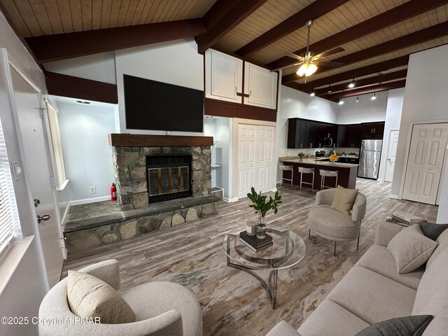 living area with a ceiling fan, wood finished floors, a fireplace, high vaulted ceiling, and beam ceiling