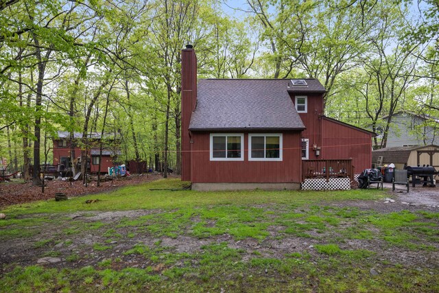 235 Scenic Dr, East Stroudsburg, PA 18302 - rear view of house with a chimney, roof with shingles, a storage unit, and an outdoor structure
