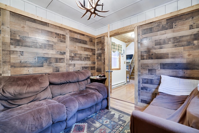 235 Scenic Dr, East Stroudsburg, PA 18302 - living room with wooden walls, a chandelier, a baseboard heating unit, wood finished floors, and stairs