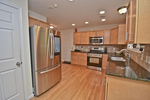 72 Chickadee Ln, Albrightsville, PA 18210 - kitchen with appliances with stainless steel finishes, a sink, light wood-style flooring, backsplash, and dark stone countertops