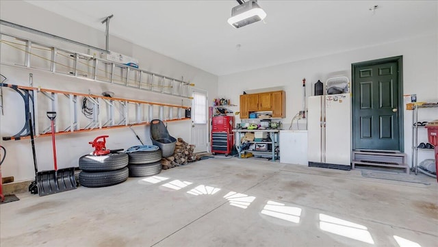 garage featuring a workshop area, a garage door opener, and freestanding refrigerator