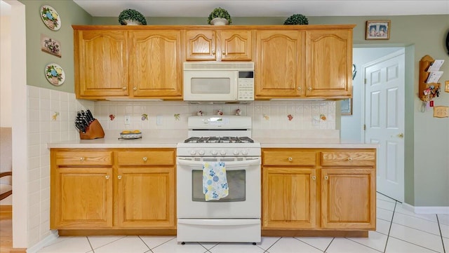 kitchen featuring light tile patterned floors, white appliances, backsplash, and light countertops