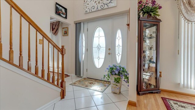 foyer entrance featuring stairway, baseboards, and wood finished floors