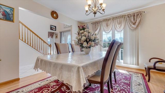 dining room with stairs, wood finished floors, baseboards, and a chandelier