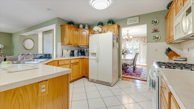 kitchen with tasteful backsplash, light countertops, light tile patterned floors, white appliances, and a sink