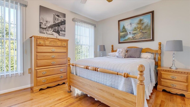 bedroom featuring multiple windows, baseboards, light wood-type flooring, and ceiling fan