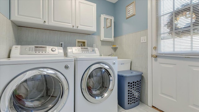 washroom with cabinet space, separate washer and dryer, tile walls, and light tile patterned flooring