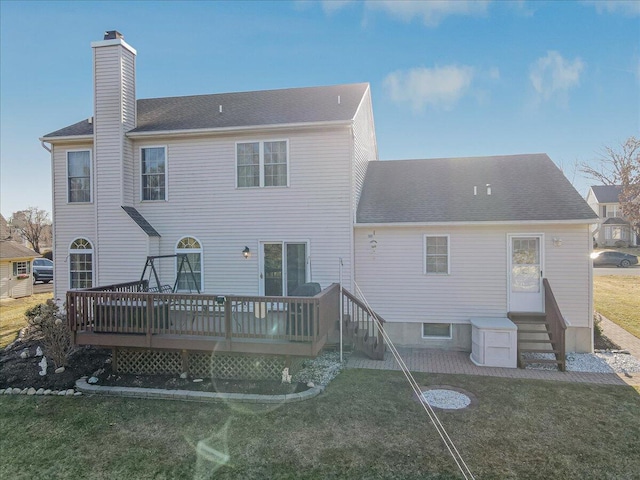 rear view of property featuring a shingled roof, entry steps, a lawn, a chimney, and a deck