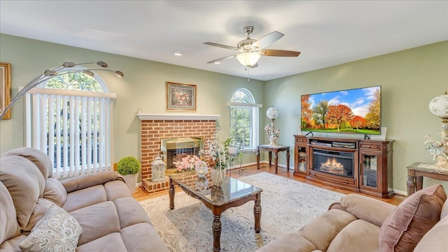 living room with a brick fireplace, wood finished floors, and a healthy amount of sunlight