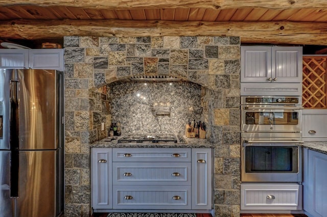 kitchen with wooden ceiling, stone counters, beam ceiling, and stainless steel appliances