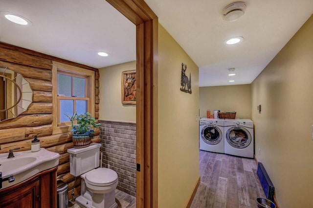 bathroom featuring independent washer and dryer, vanity, toilet, wood finished floors, and log walls