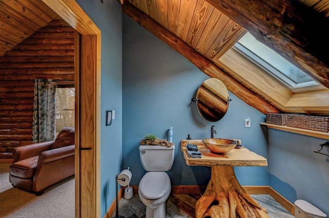 interior space featuring log walls, a sink, toilet, lofted ceiling with skylight, and wooden ceiling