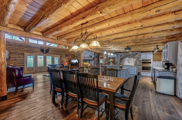 dining space featuring a healthy amount of sunlight, wood ceiling, rustic walls, and dark wood finished floors
