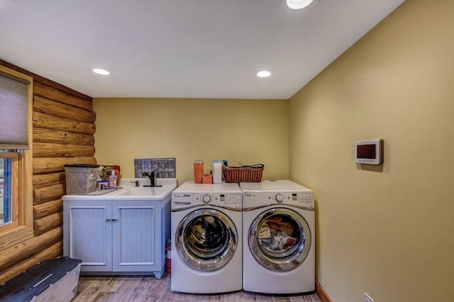 washroom with separate washer and dryer, a sink, log walls, light wood finished floors, and cabinet space