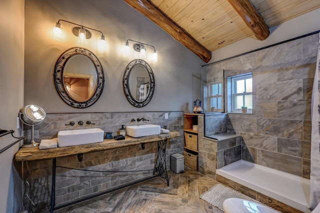 bathroom featuring lofted ceiling with beams, tiled shower, wooden ceiling, a sink, and tile walls