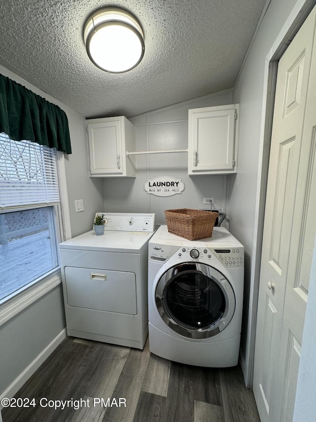 laundry area featuring washing machine and clothes dryer, cabinet space, dark wood-type flooring, a textured ceiling, and baseboards