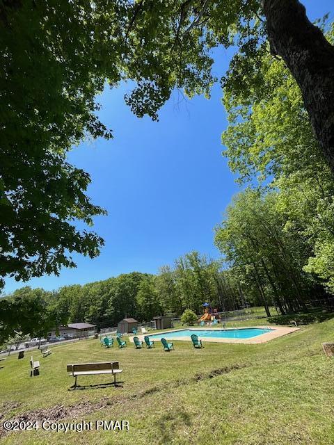 surrounding community featuring a lawn, a swimming pool, and a storage unit