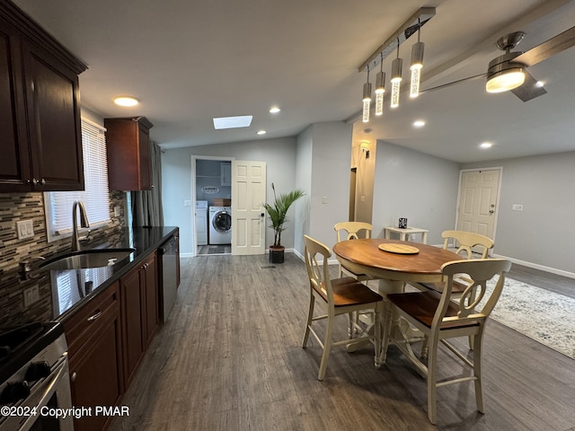 dining room with vaulted ceiling with skylight, baseboards, dark wood-style flooring, and independent washer and dryer