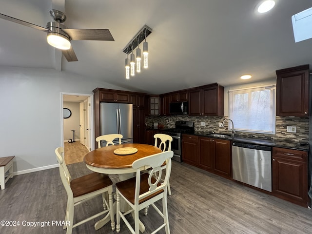 kitchen featuring light wood finished floors, appliances with stainless steel finishes, dark countertops, and a sink