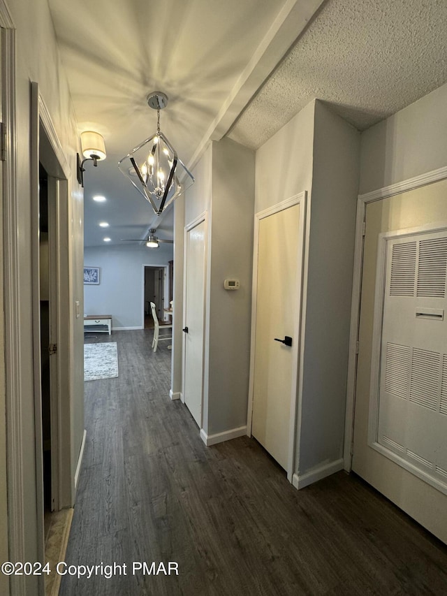 hallway featuring dark wood-style floors, a heating unit, a chandelier, and baseboards