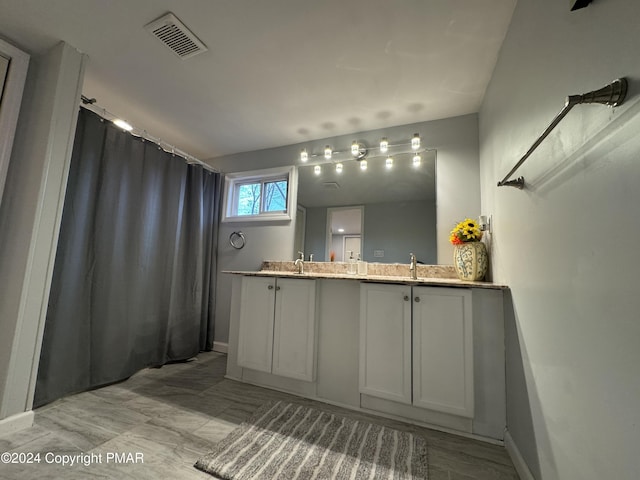 bathroom featuring double vanity, visible vents, a shower with shower curtain, a sink, and baseboards