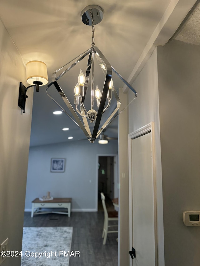 hall featuring baseboards, wood finished floors, and an inviting chandelier