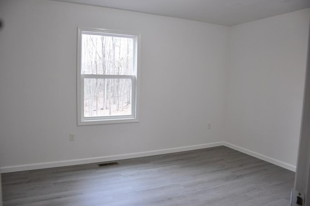 empty room featuring visible vents, baseboards, and wood finished floors