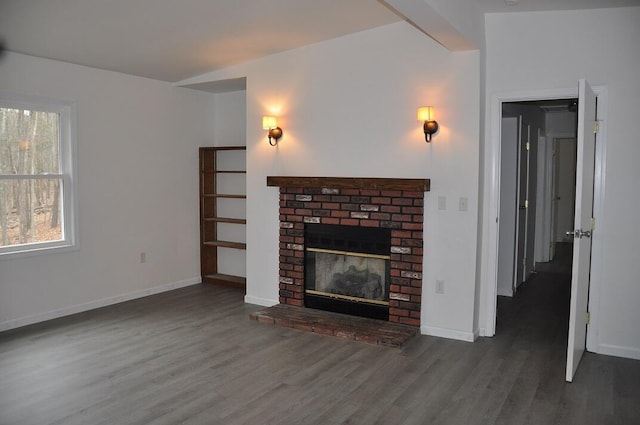 unfurnished living room featuring a fireplace, baseboards, and wood finished floors