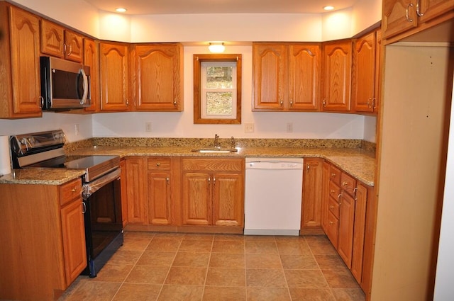 kitchen with a sink, stainless steel appliances, light stone countertops, and brown cabinetry