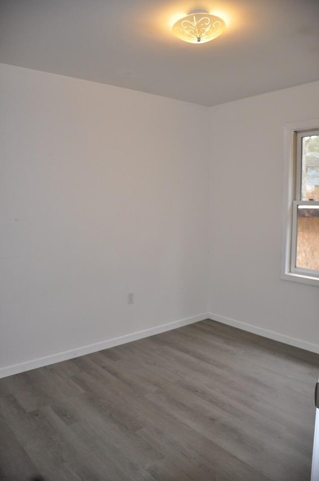 empty room featuring baseboards and dark wood-style flooring