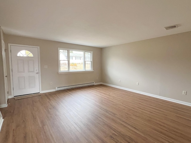 foyer entrance with a baseboard heating unit, baseboards, visible vents, and wood finished floors