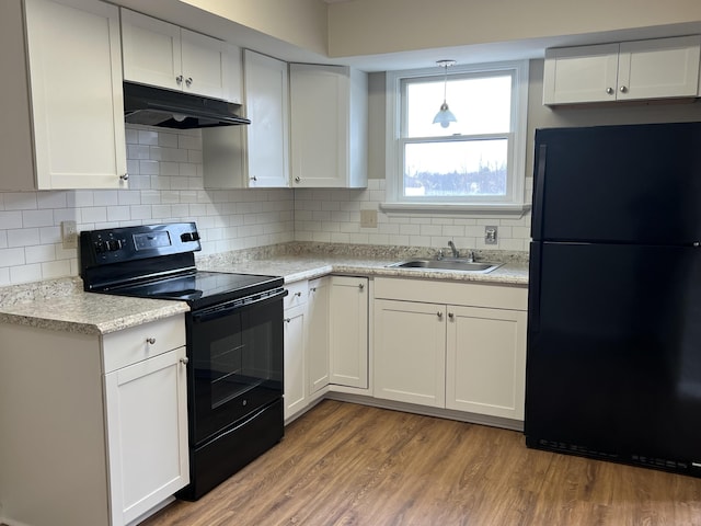 kitchen featuring black appliances, under cabinet range hood, a sink, wood finished floors, and white cabinets