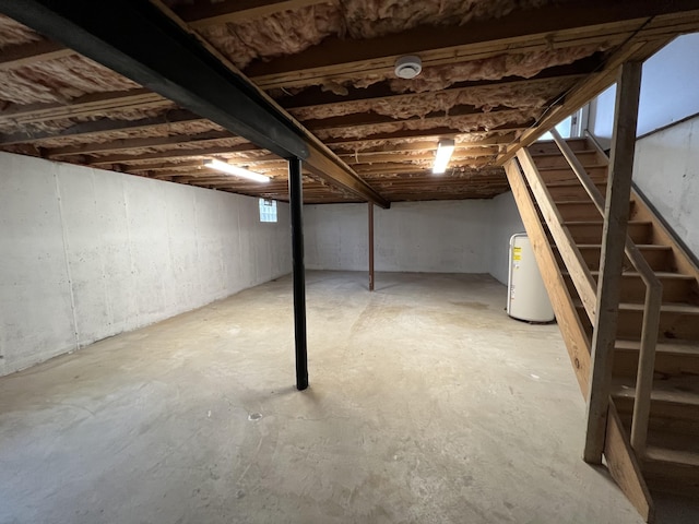 unfinished below grade area featuring stairs and water heater