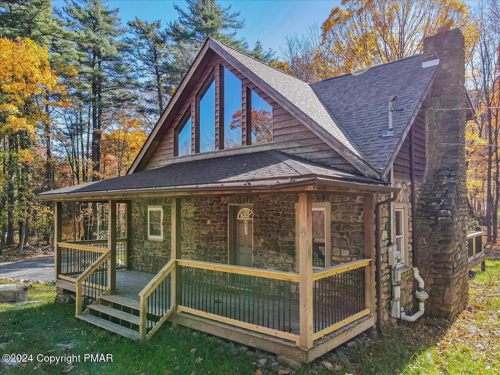 exterior space featuring roof with shingles, a porch, a chimney, and stone siding