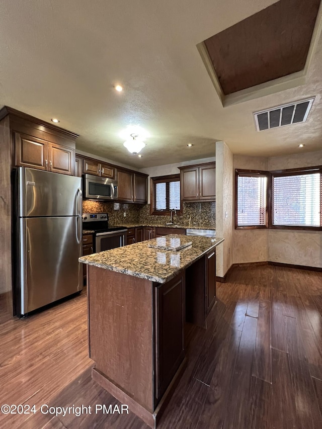 kitchen with appliances with stainless steel finishes, visible vents, backsplash, and dark wood-type flooring