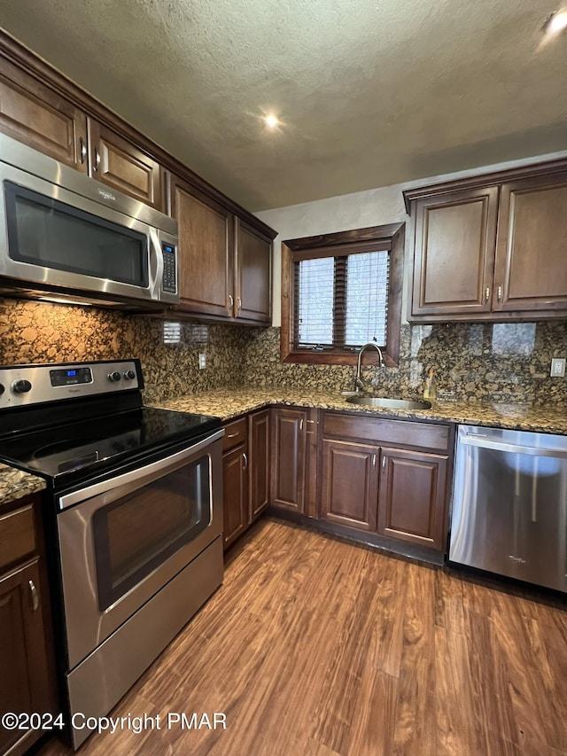 kitchen with dark wood-style floors, appliances with stainless steel finishes, a sink, and dark brown cabinetry