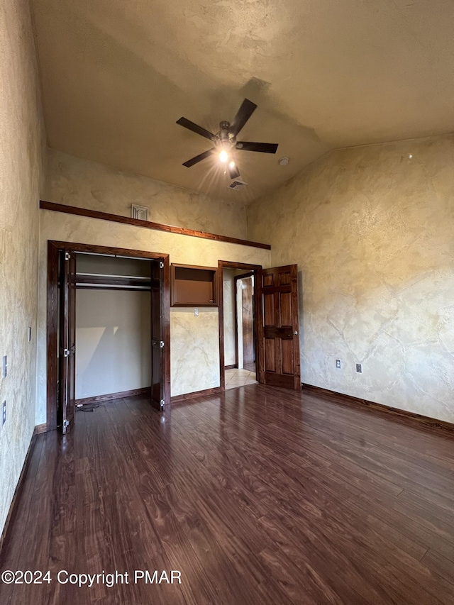 unfurnished living room with ceiling fan, high vaulted ceiling, dark wood-style flooring, visible vents, and baseboards