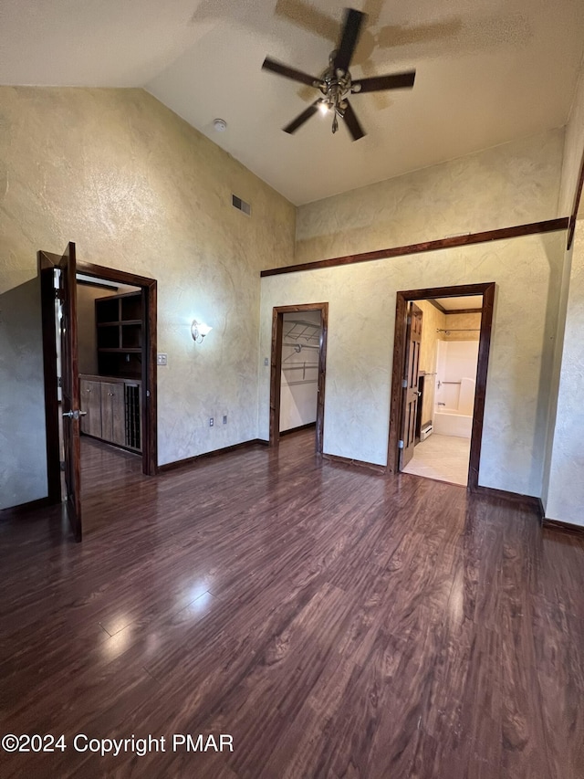 interior space featuring visible vents, a textured wall, wood finished floors, high vaulted ceiling, and baseboards