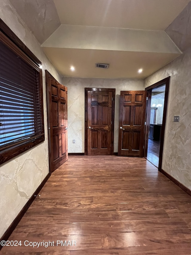 interior space featuring visible vents, a textured wall, baseboards, and wood finished floors