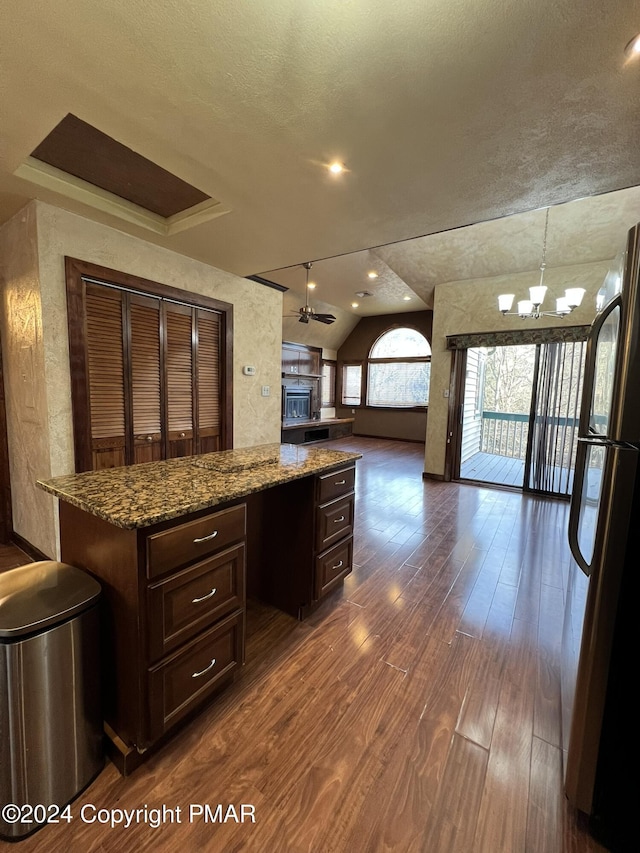 kitchen featuring lofted ceiling, open floor plan, dark wood-type flooring, a center island, and freestanding refrigerator