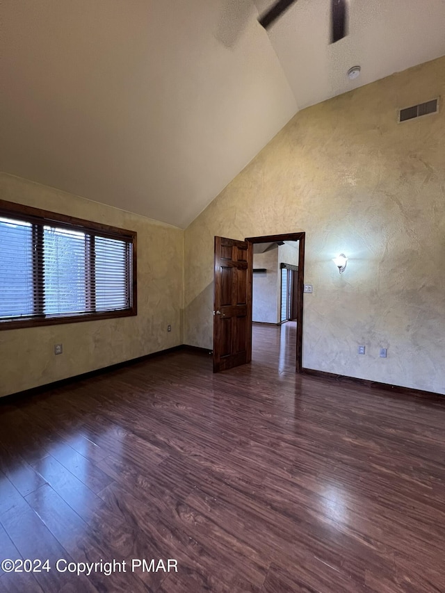 spare room featuring lofted ceiling, visible vents, baseboards, and wood finished floors