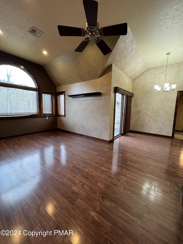 unfurnished living room featuring ceiling fan with notable chandelier, visible vents, vaulted ceiling, and wood finished floors