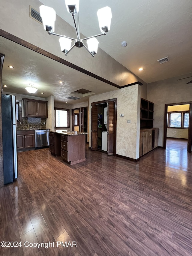 kitchen with dark brown cabinetry, stainless steel appliances, dark wood-style flooring, open floor plan, and a center island